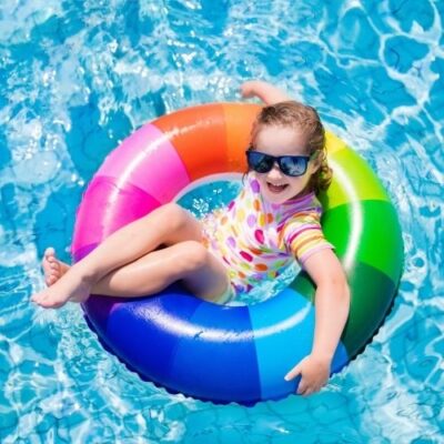 A young child smiling while floating in the pool.