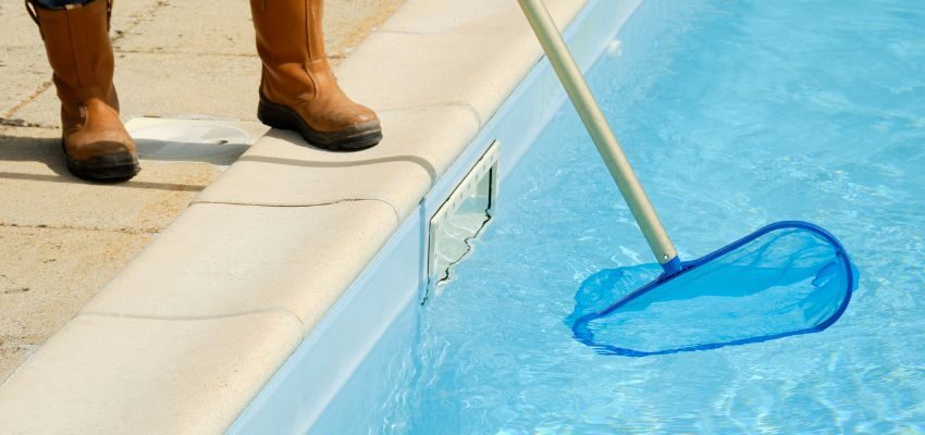 Someone cleaning a swimming pool.