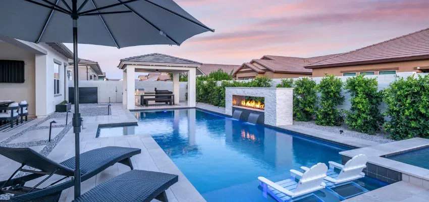 Luxury backyard pool featuring a baja shelf with sun loungers and umbrellas.