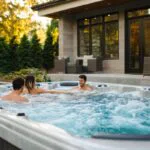 A group of friends enjoys swimming in an inground pool hot tub combo.