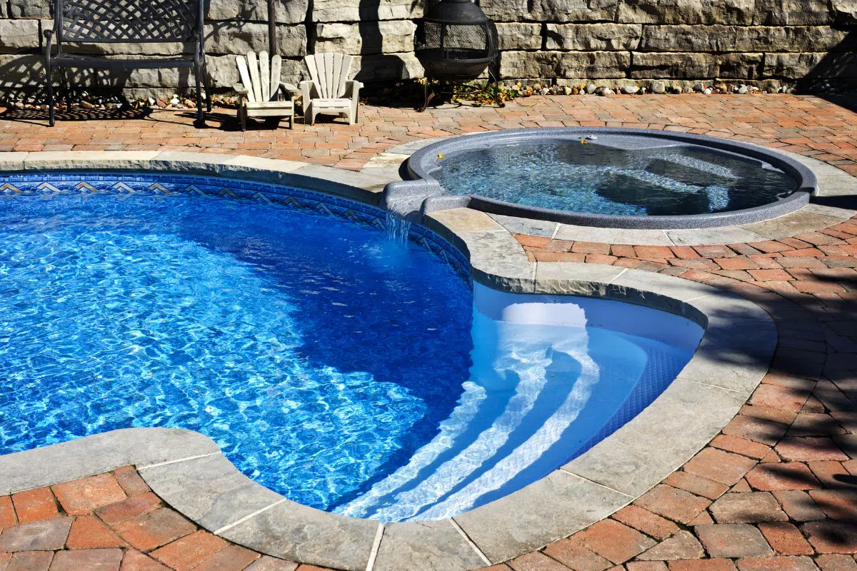 An inground hot tub pool combo, also called a spa pool combo, is a unique design. It seamlessly combines a swimming pool and a hot tub or spa within a single space.