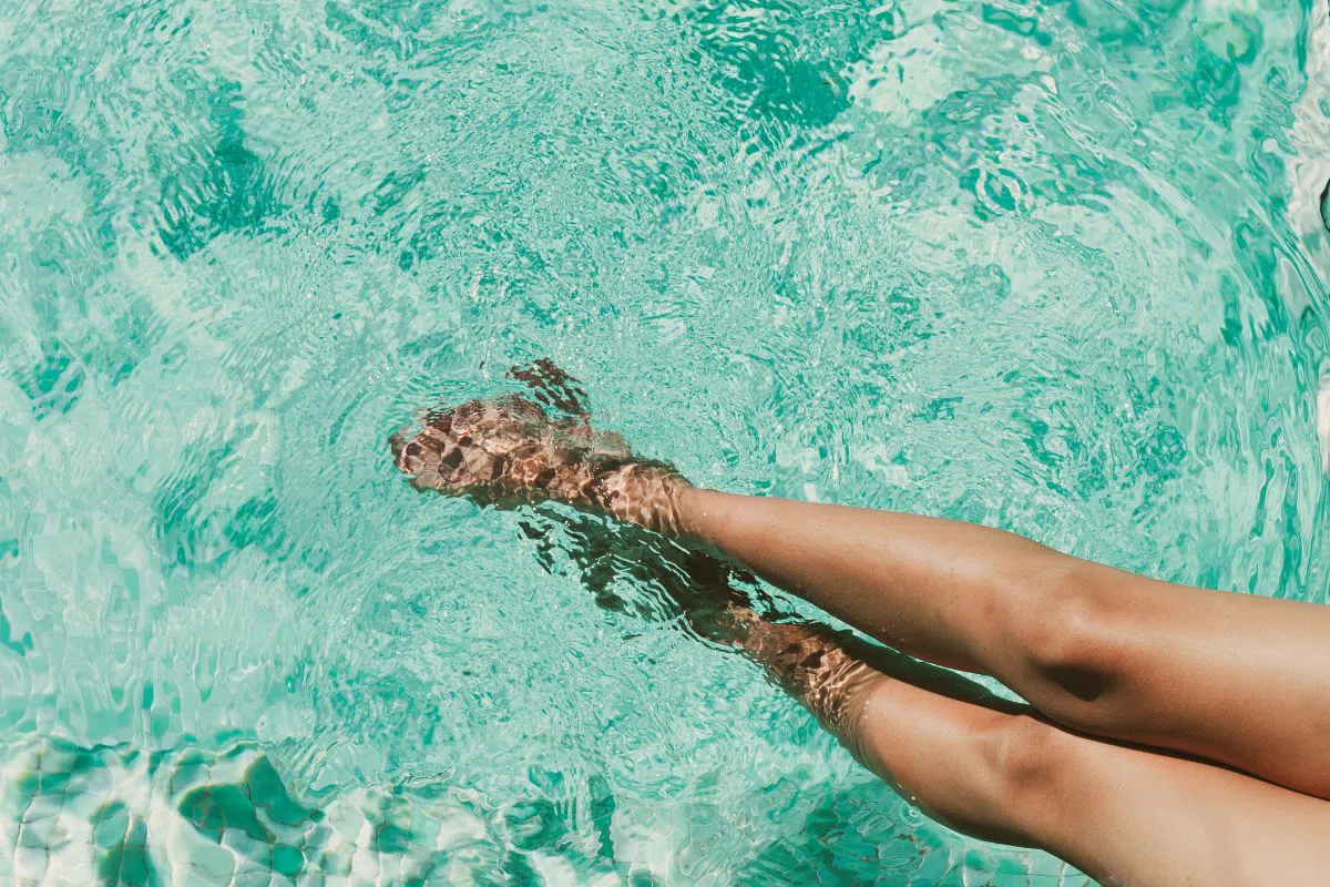 The woman loves to soak her feet in a clear water pool.