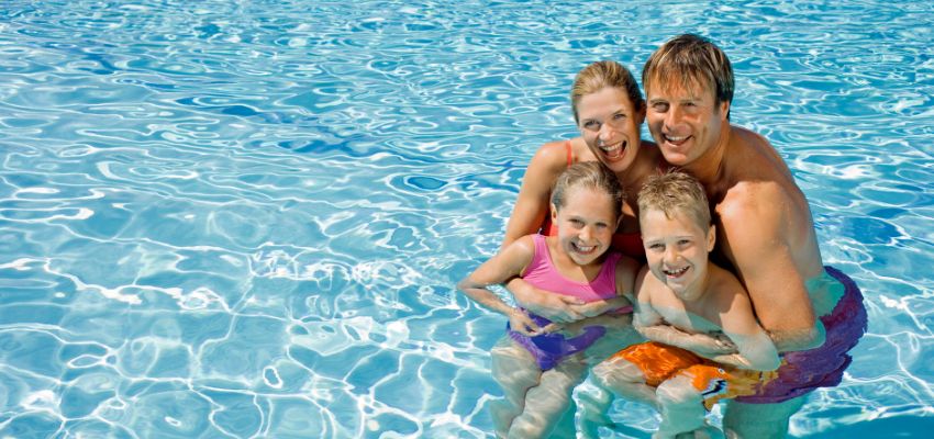 A happy family enjoys swimming in a pool together.