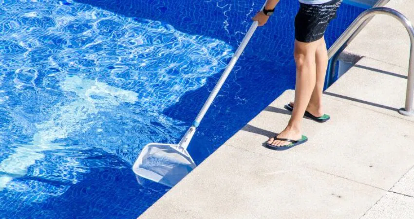 The homeowner cleans the pool to remove dead algae.