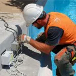 The technician installs electricity around the pool.