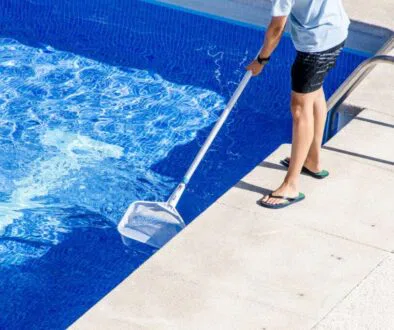 The man is cleaning the pool.